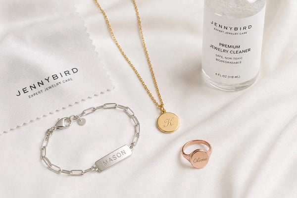 Gold, sterling silver, and rose gold personalized jewelry pieces with cleaning supplies