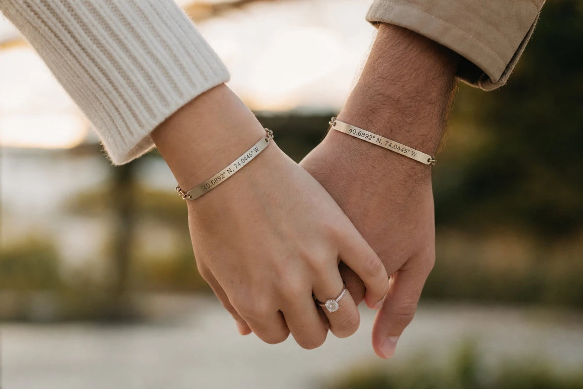 Couple holding hands wearing matching personalized coordinates bracelets