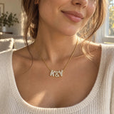 Gold zircon 3D bubble letter necklace spelling K&Y, worn with a cream knit top.