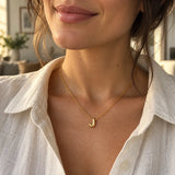 Polished gold 3D bubble letter J necklace worn with a white linen shirt.