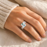 Two-name birthstone ring worn on a hand in warm natural light