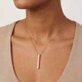 Necklace with a vertical bar pendant on a neutral background