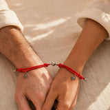Two people wearing red magnetic couple bracelets with the charms joined
