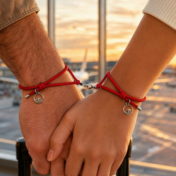 Two people wearing matching red magnetic couple bracelets while holding hands