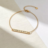 Gold bracelet with engraved coordinates on a light background