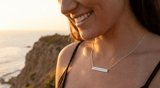 Woman wearing a coordinates necklace with a scenic ocean view in the background